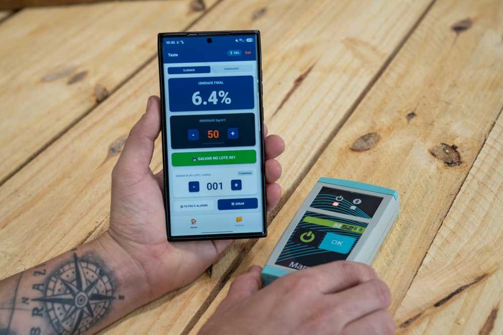 operador usando medidor de umidade Bluetooth em pilha de madeira serrada